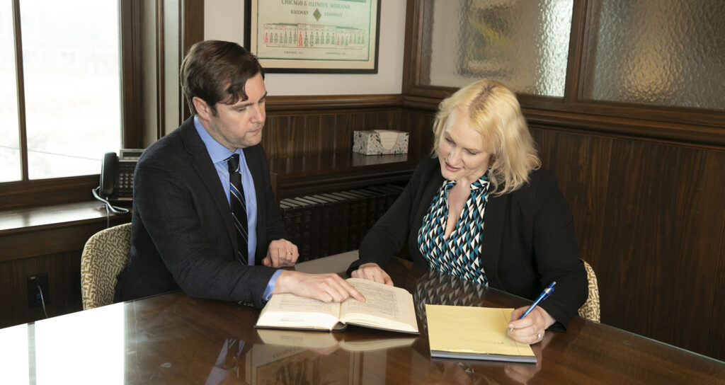 Attorney Dan Noll and Attorney Sarah Noll in suits sitting at desk