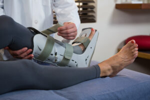 Physiotherapist tying leg pad - Jacksonville Workers Compensation Lawyer Near You [Free Consultation] - Jacksonville Workers Comp Attorney Near Me - Jacksonville Worker Compensation Law Firm - Illinois Workers Compensation Attorneys - Noll Law Office